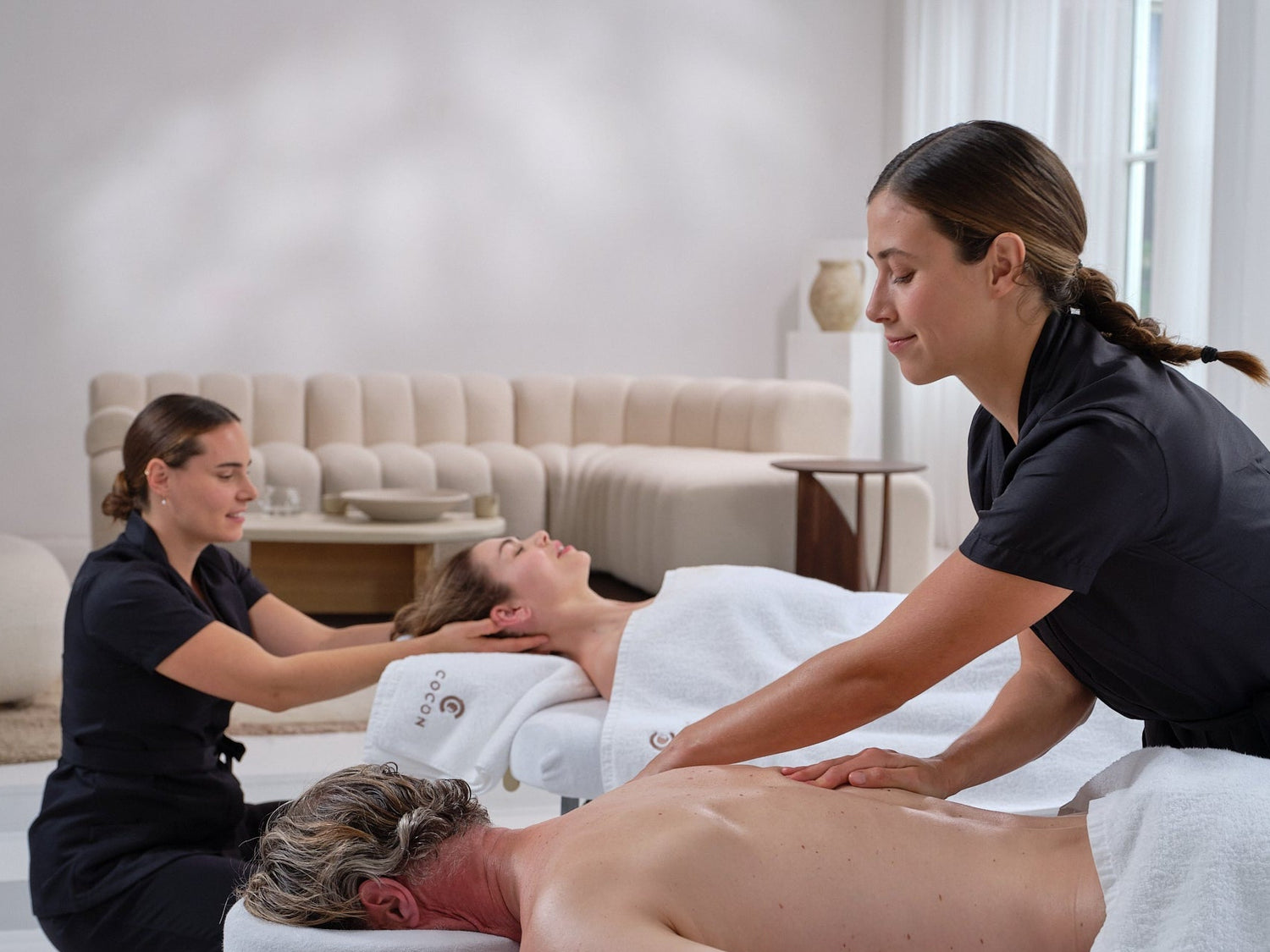 Two professional COCON Group spa therapists delivering a flawless couples massage in a luxury hotel environment, highlighting premium career opportunities for elite wellness professionals.